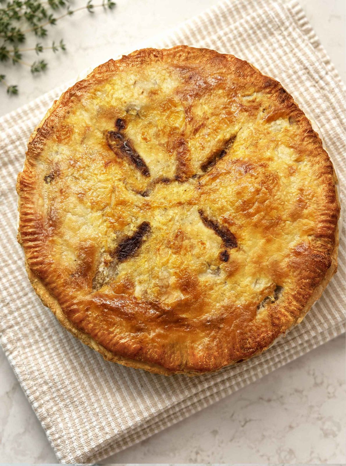 Whole homemade beef pot pie fresh from the oven with a deep golden, flaky top crust
