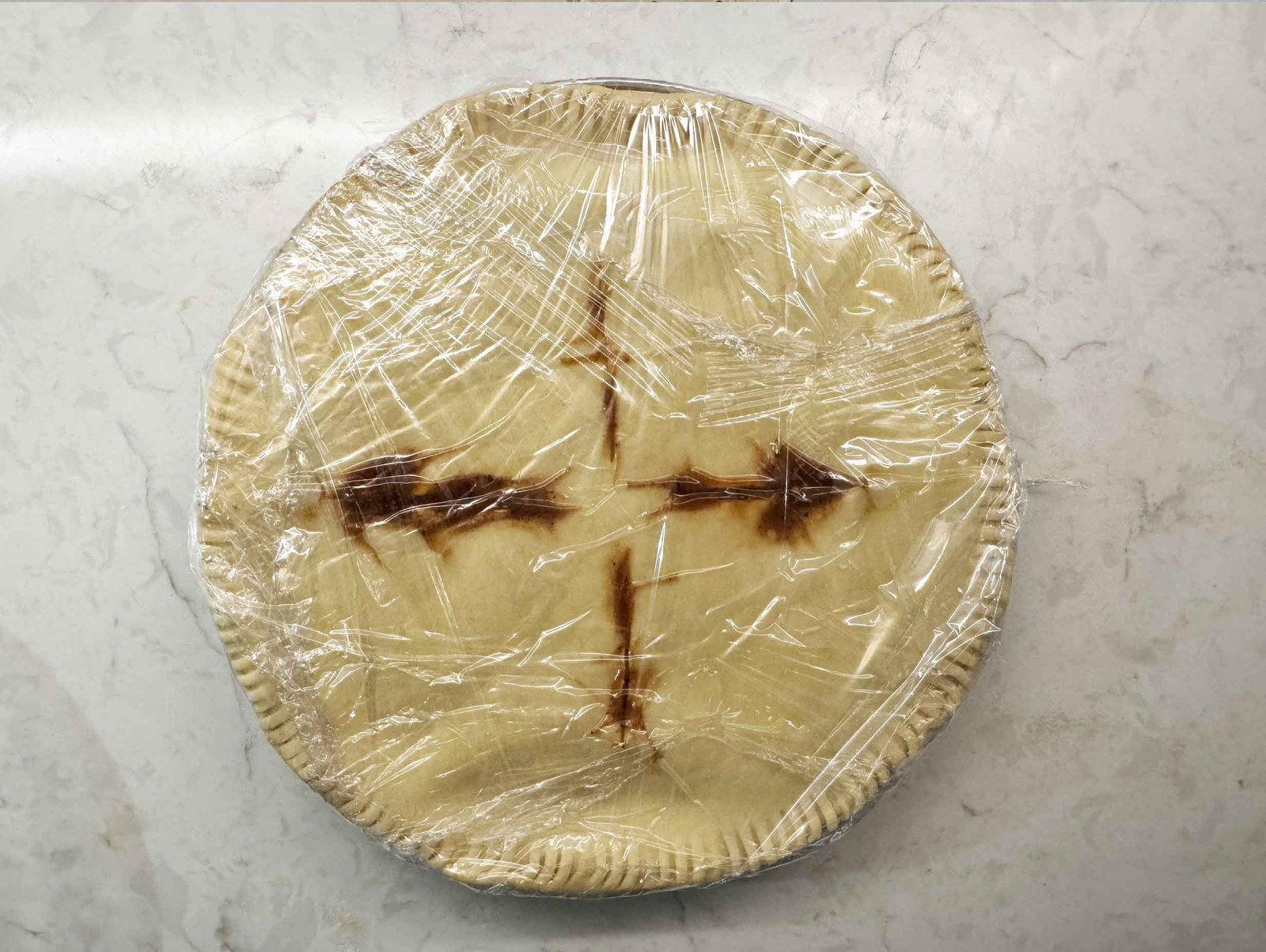 Unbaked beef pot pie wrapped tightly in plastic wrap, ready for the freezer