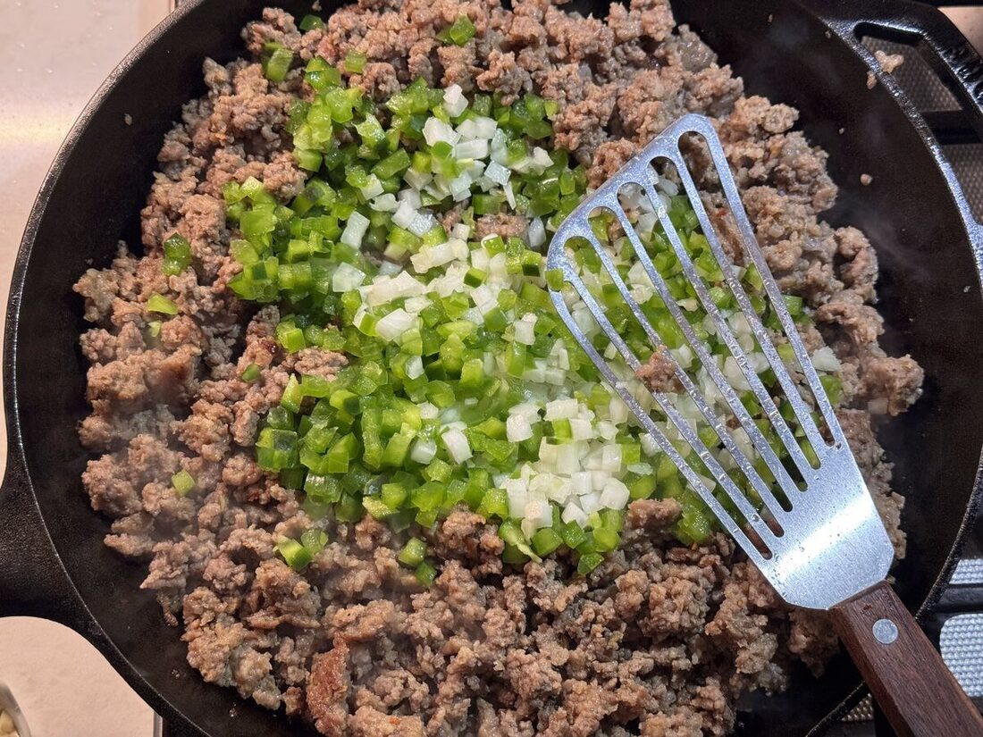 Ground beef browning in a skillet with onions and garlic