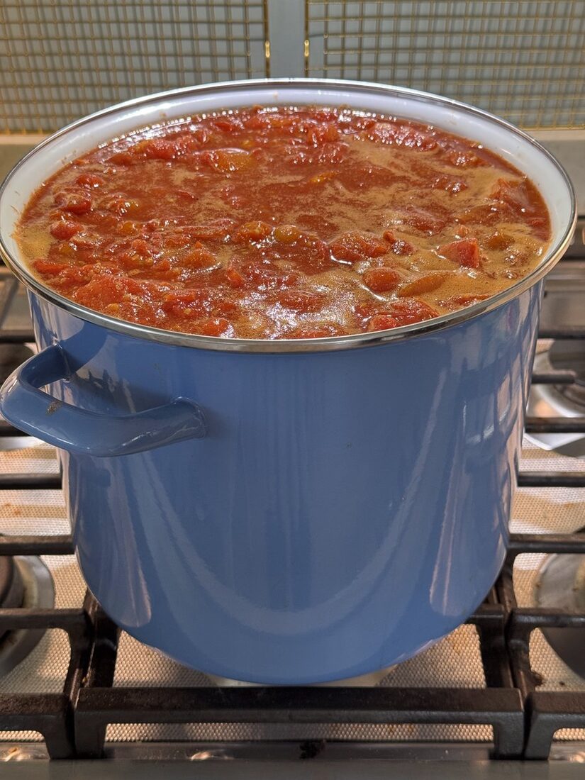 A big blue stockpot of tomatoes cooking down on the stove