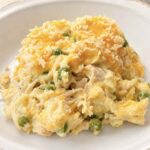 A bowl of creamy chicken noodle casserole with peas and a golden panko topping