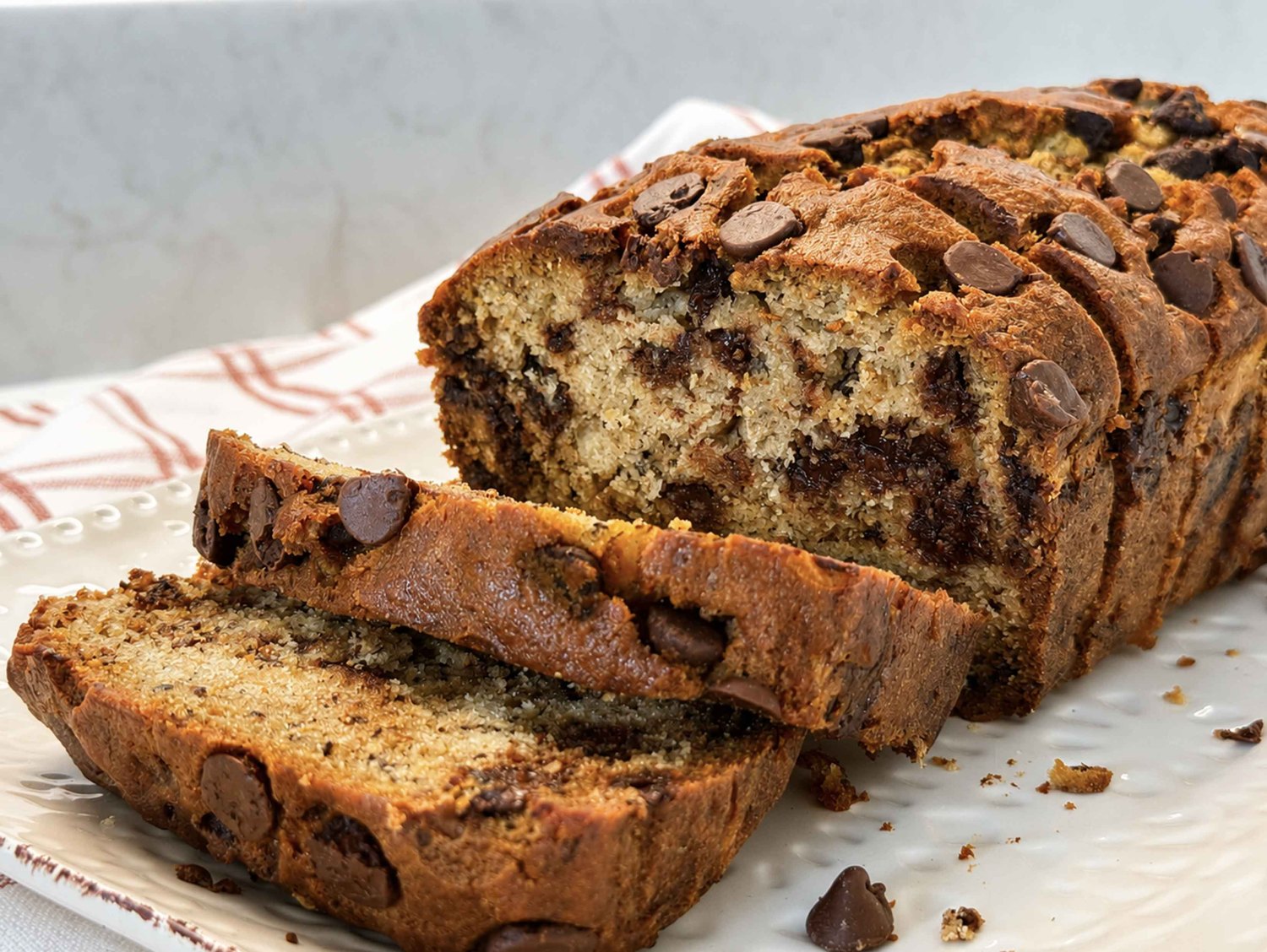 Chocolate chip banana bread loaf with thick slices cut and fanned forward, showing a moist crumb full of melty chocolate chips