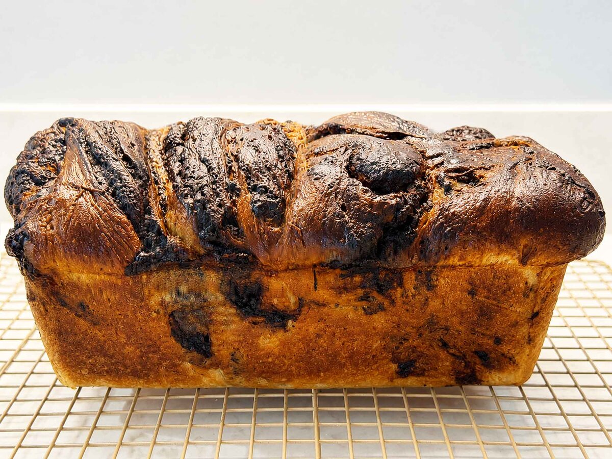 Golden baked chocolate sourdough babka loaf cooling on a wire rack
