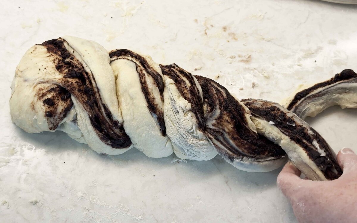 Twisting the two halves of babka dough together into a braid, cut sides up
