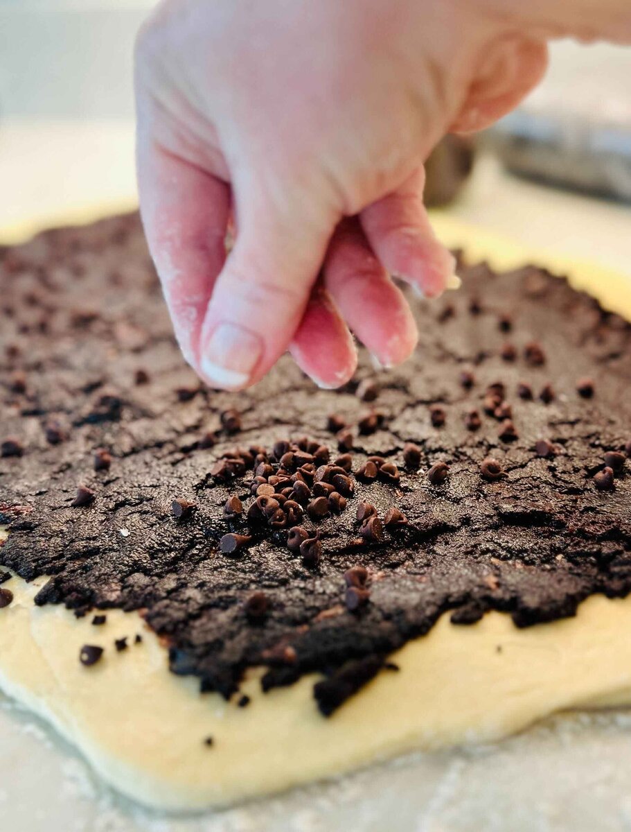 Sprinkling mini chocolate chips over the chocolate filling on the babka dough