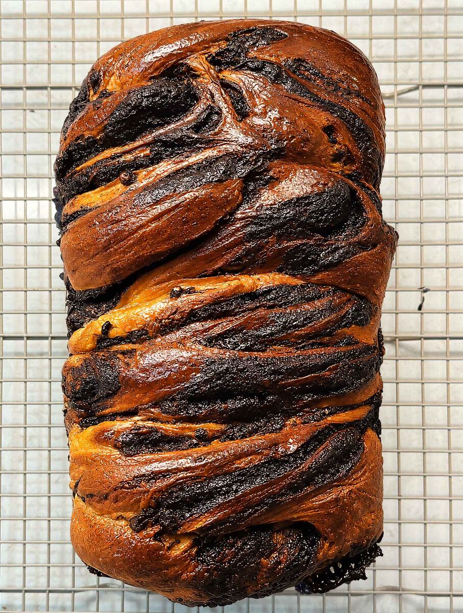 Overhead view of a baked chocolate sourdough babka loaf with glossy chocolate swirls on top