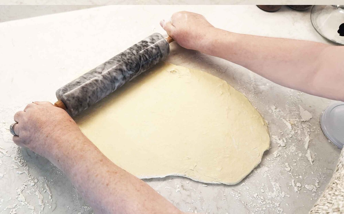 Rolling the chilled babka dough into a rectangle on a floured counter with a marble rolling pin