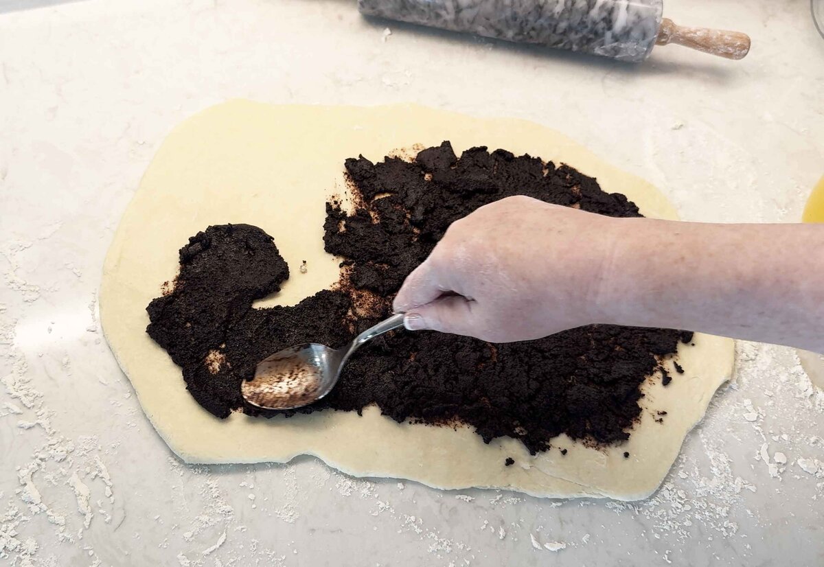 Spreading the chocolate filling over the rolled-out babka dough with a spoon