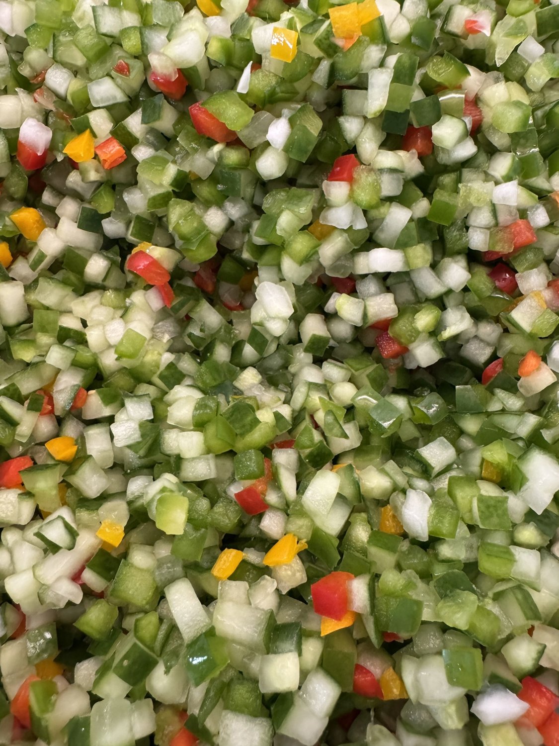 Close-up of finely chopped cucumbers, green peppers, and red peppers for sweet relish