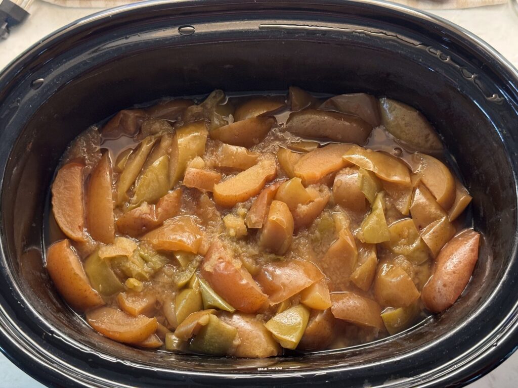 Soft golden cooked apples collapsed in the bottom of a slow cooker