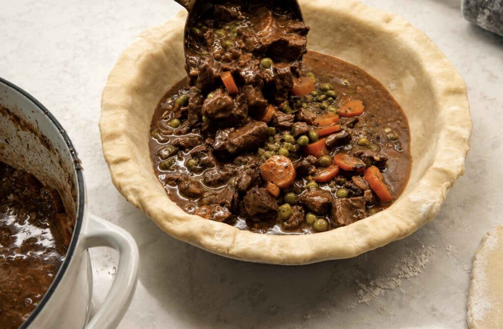 Ladling beef filling into a homemade pie crust