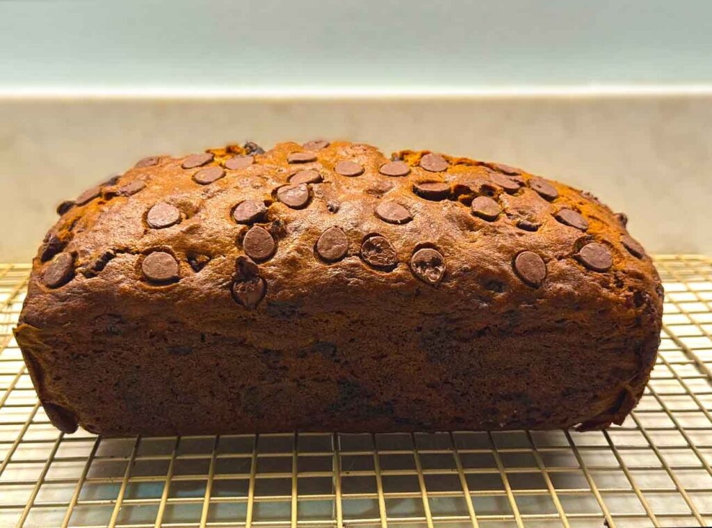 Baked chocolate chip banana bread loaf cooling on a wire rack