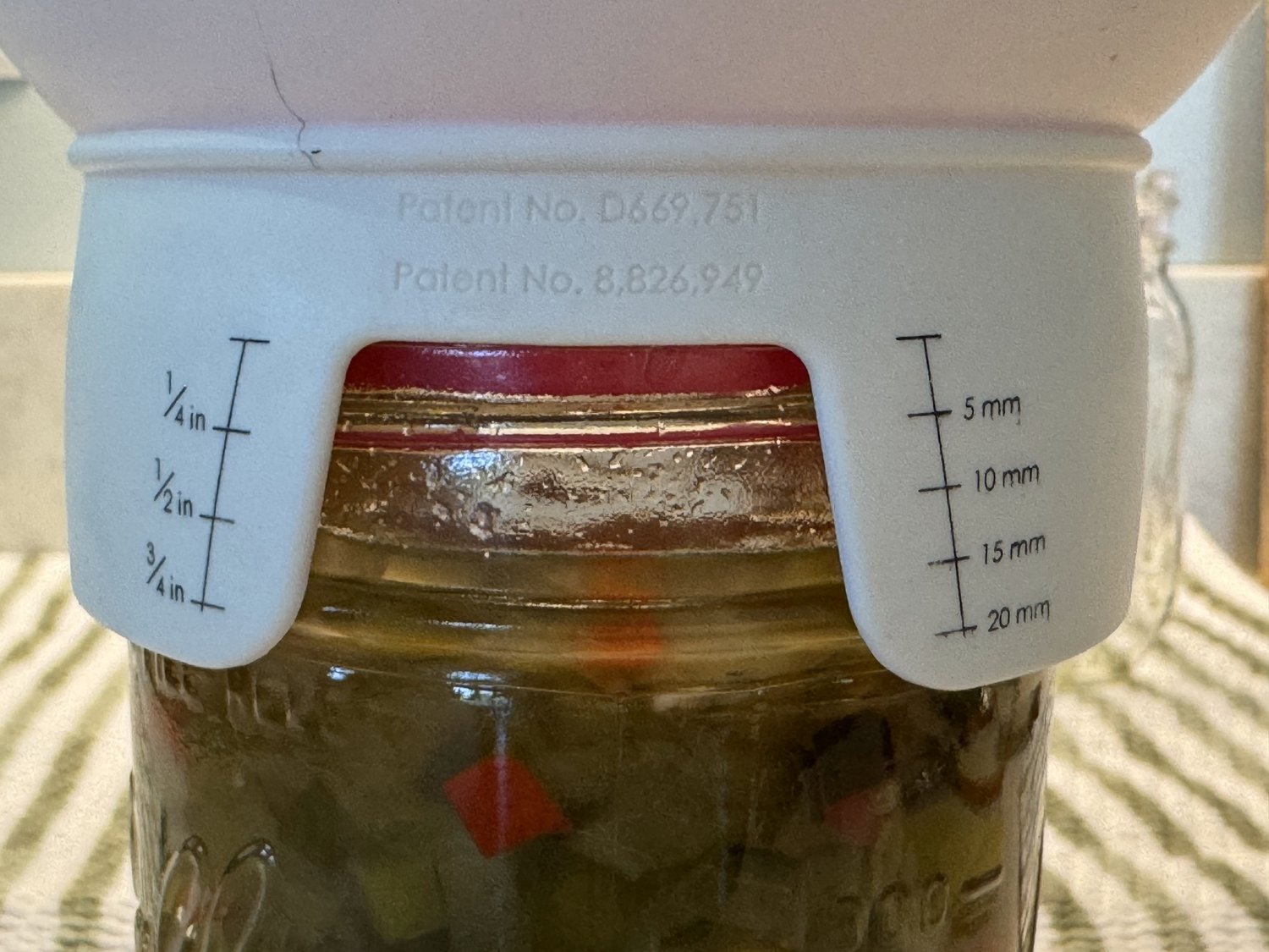 Measuring half-inch headspace at the top of a filled relish jar