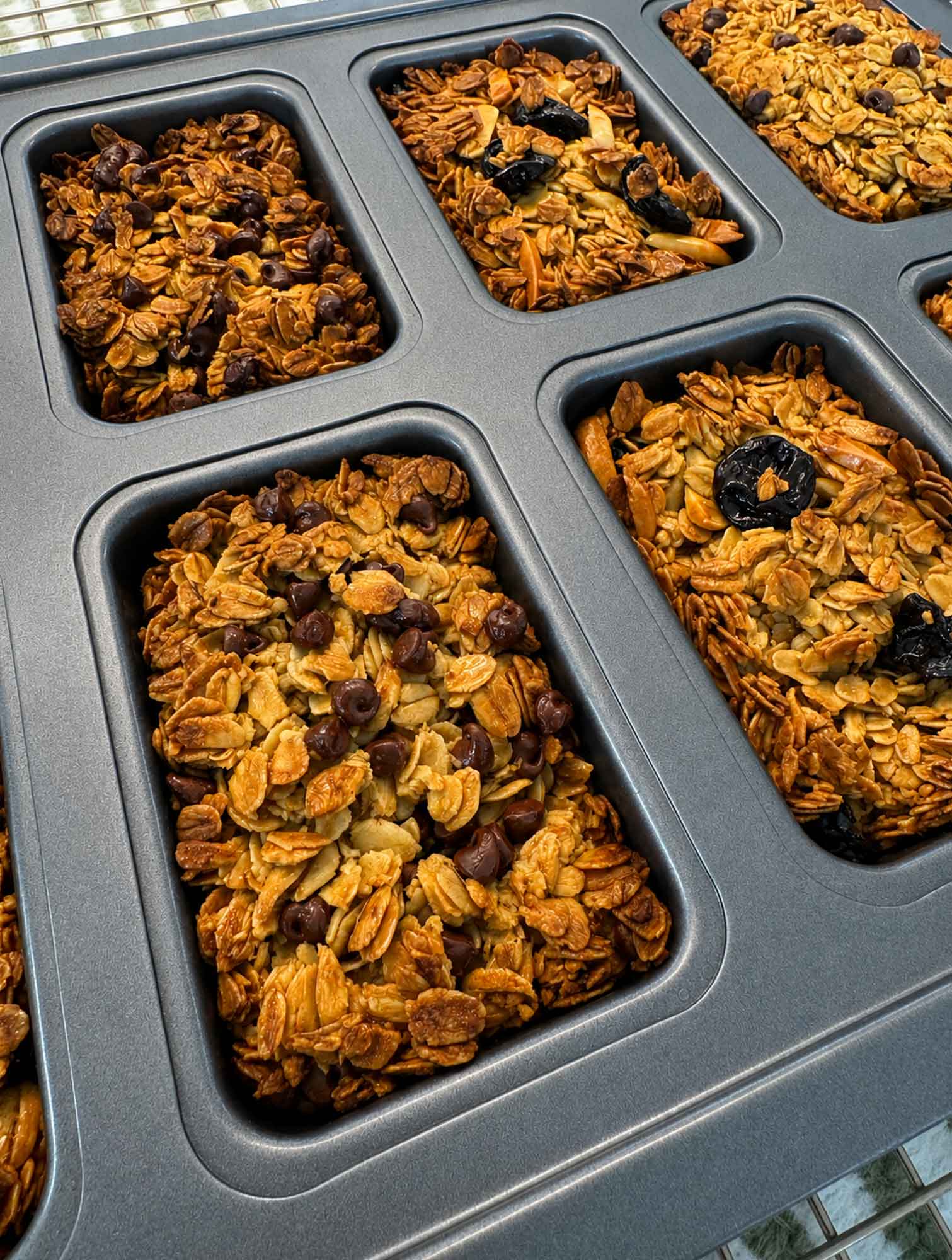 A mini loaf pan holding baked oatmeal breakfast bars in different flavors, each a neat uniform rectangle.