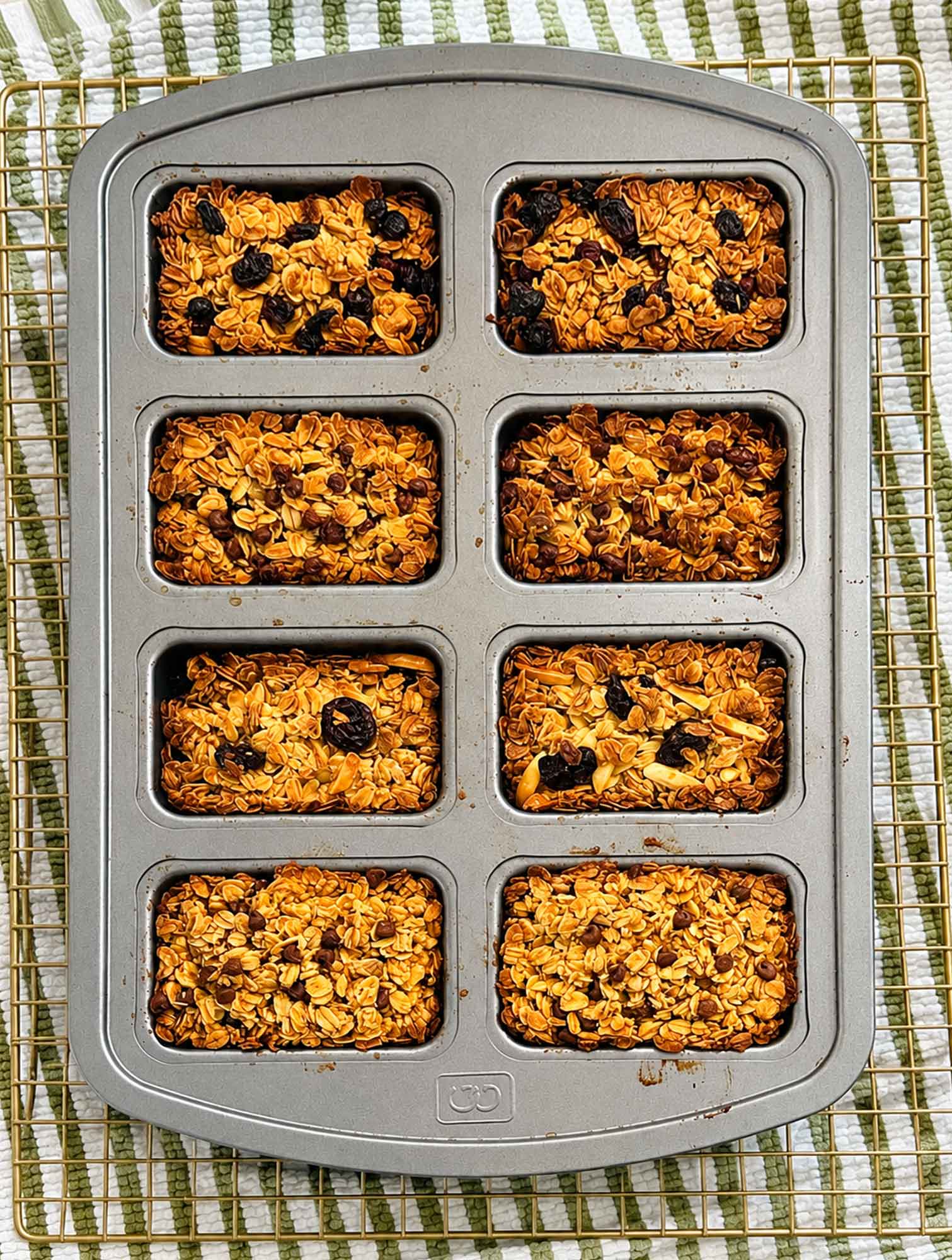 A full mini loaf pan of baked oatmeal breakfast bars resting on a wire rack to cool.