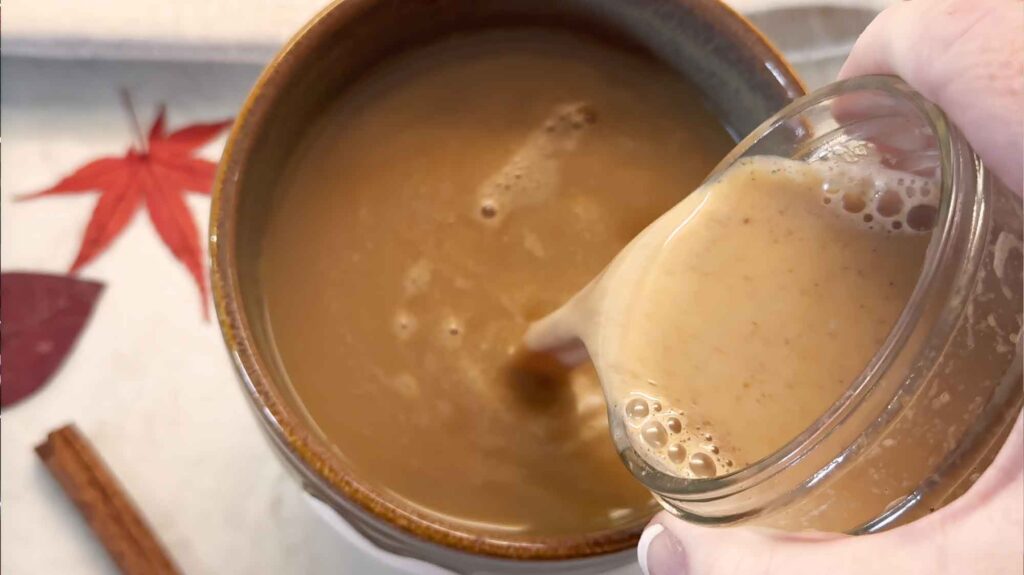 Pouring pumpkin creamer in coffee cup