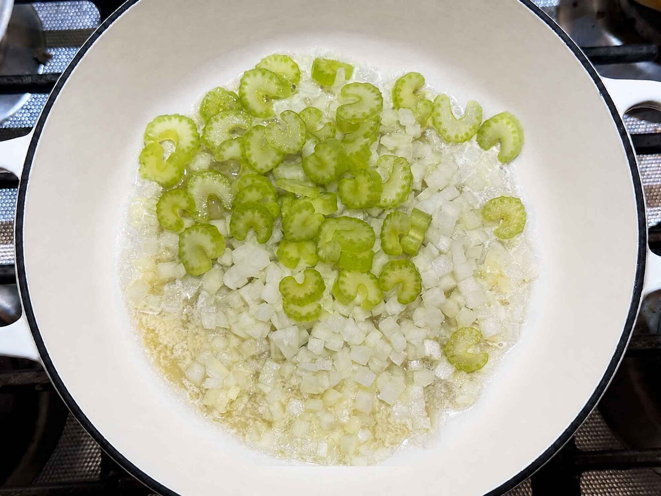 Diced onion and celery softening in melted butter in a pot