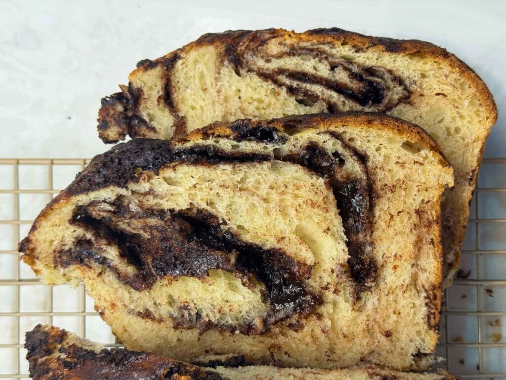 Two slices of chocolate sourdough babka on a cooling rack
