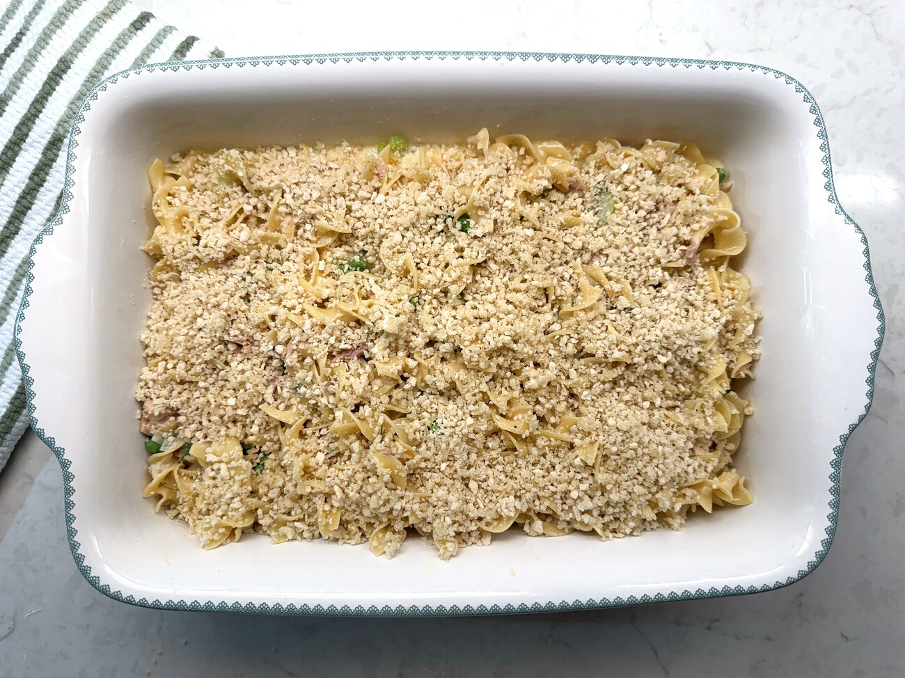 Assembled tuna noodle casserole topped with buttered breadcrumbs, ready to bake