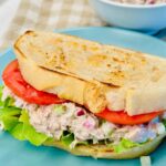 Tuna salad sandwich on toasted sourdough with lettuce and tomato on a blue plate