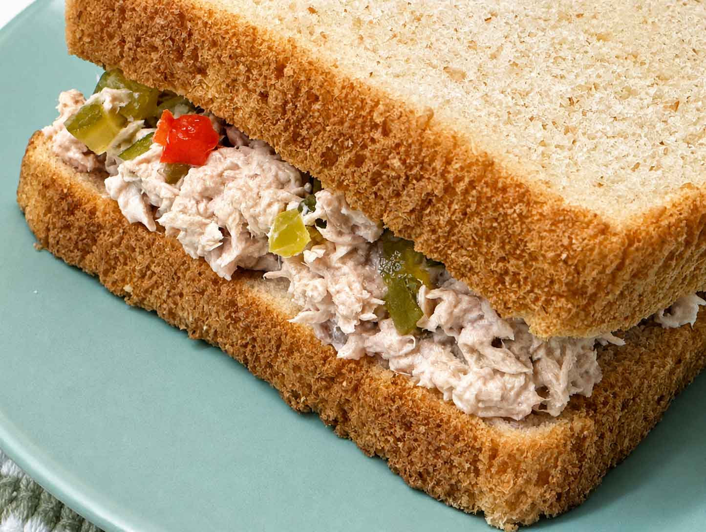 A tuna salad sandwich on wheat bread with sweet pickle relish visible in the filling