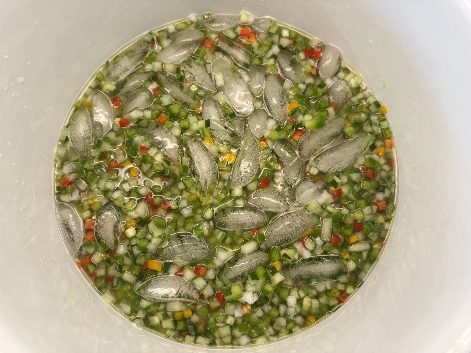 Chopped relish vegetables soaking in salt and ice water in a bowl