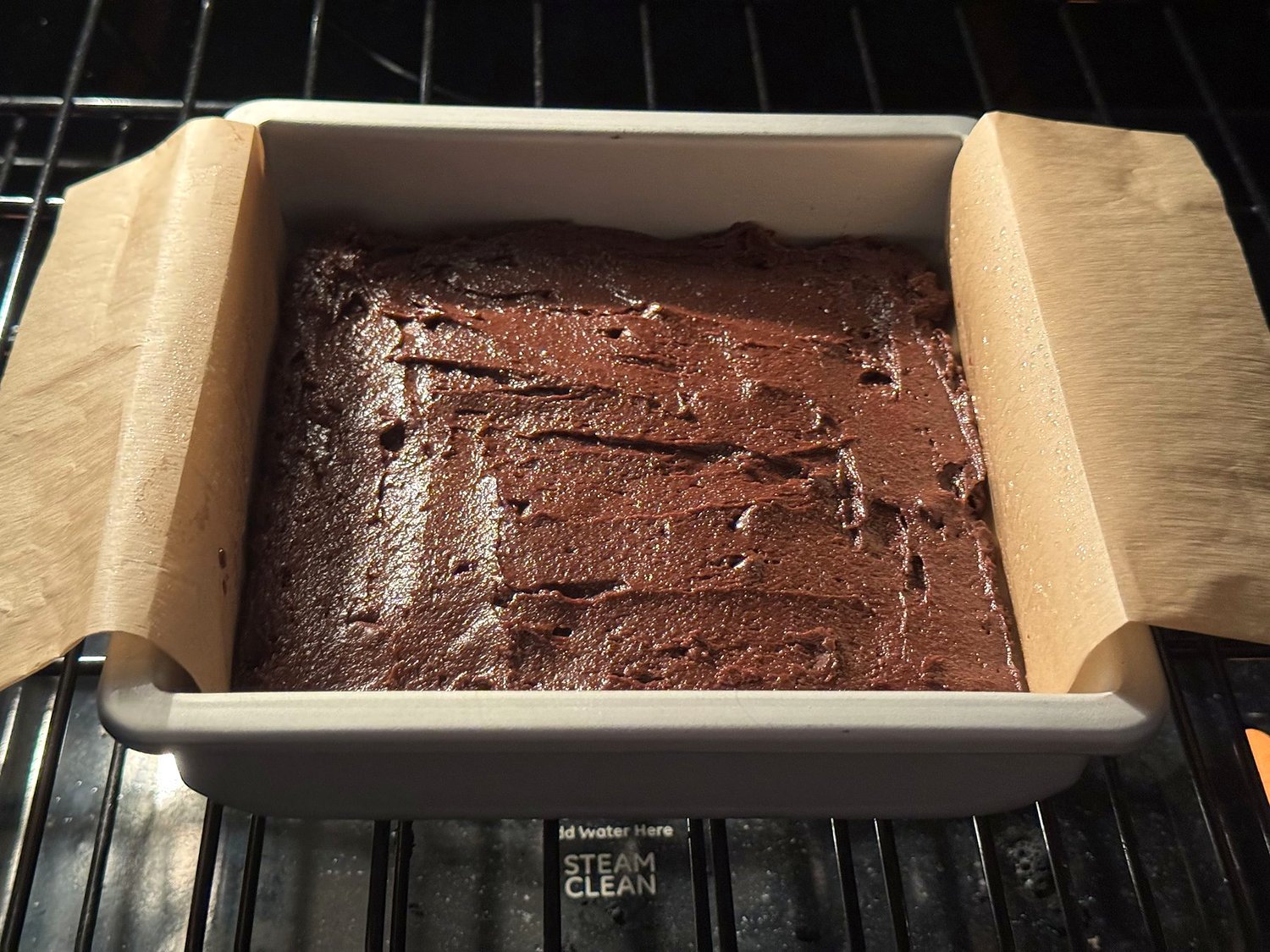 An 8x8 pan of brownies baking on the middle rack of the oven