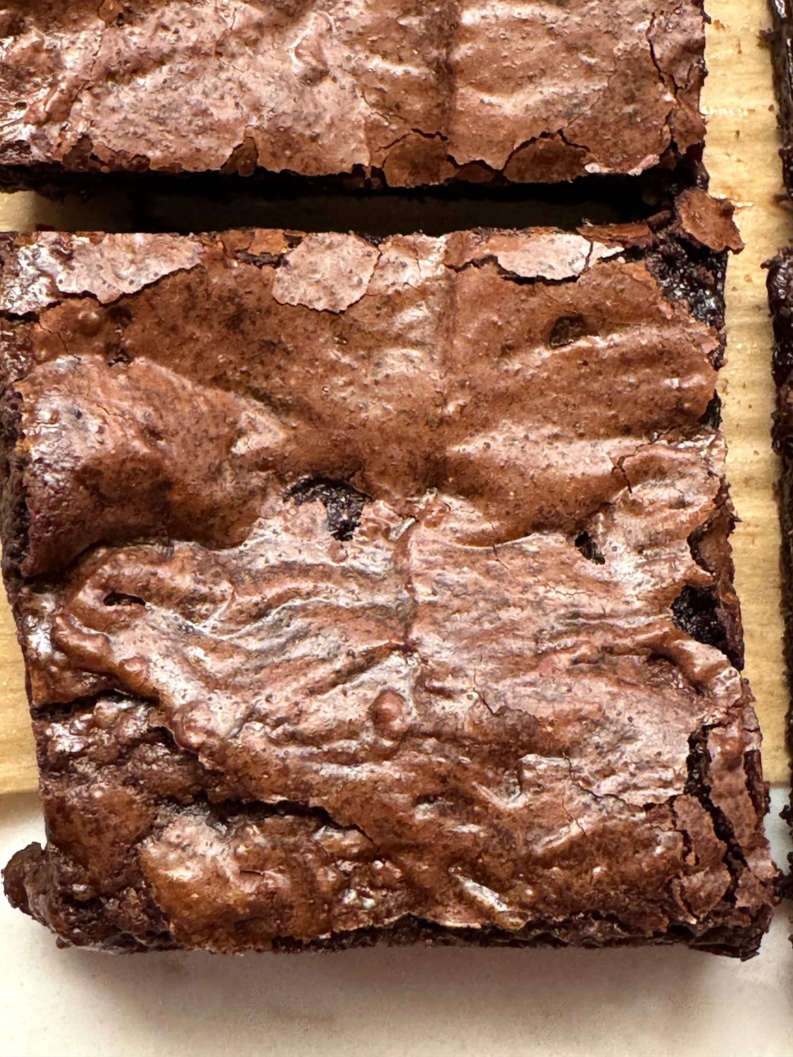 Close-up of a cut brownie showing the shiny, paper-thin crackly top