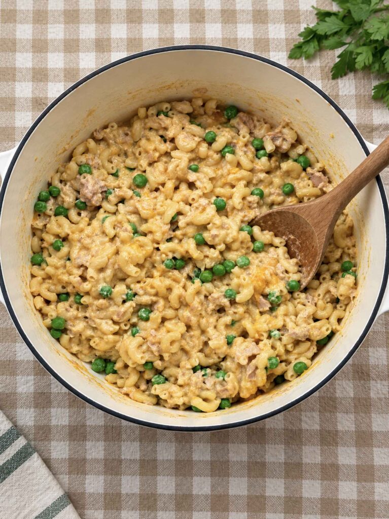 A big pot of creamy tuna pasta with a wooden serving spoon