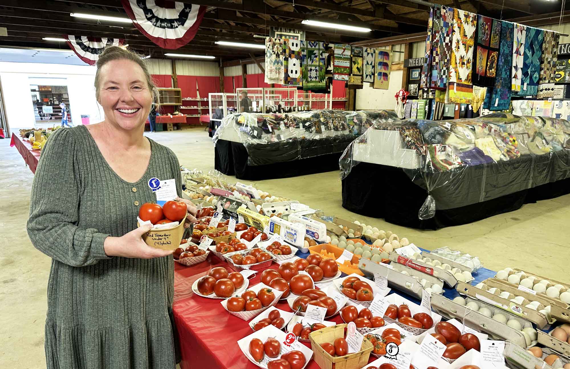 Jennifer holding a basket of first place red tomatoes at the county fair agriculture display.