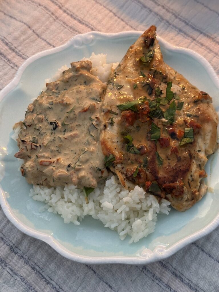 He Married Me Chicken served over white rice on a blue plate, garnished with fresh basil