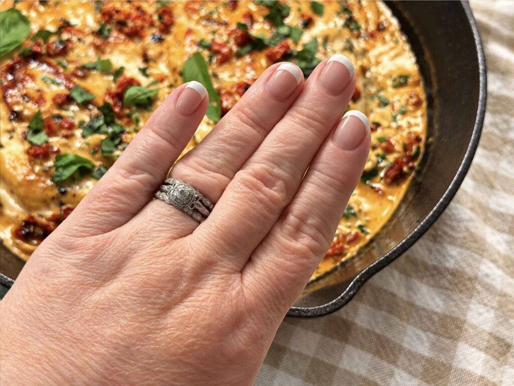 Jennifer's wedding ring on her left hand with the marry me chicken in the background