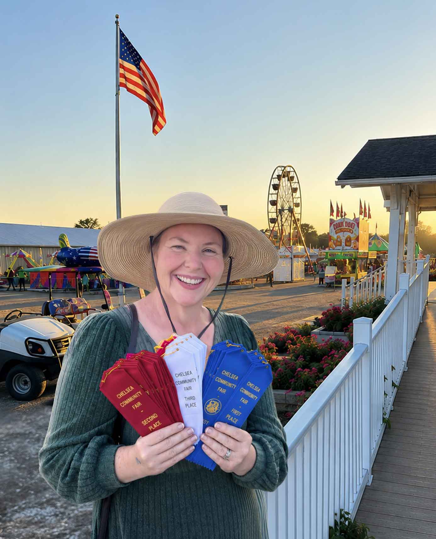 Jennifer holding dozens of Chelsea Community Fair ribbons at sunset with the Ferris wheel behind her.
