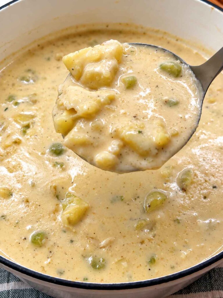 A ladle filled with potato soup with big chunks of potatoes