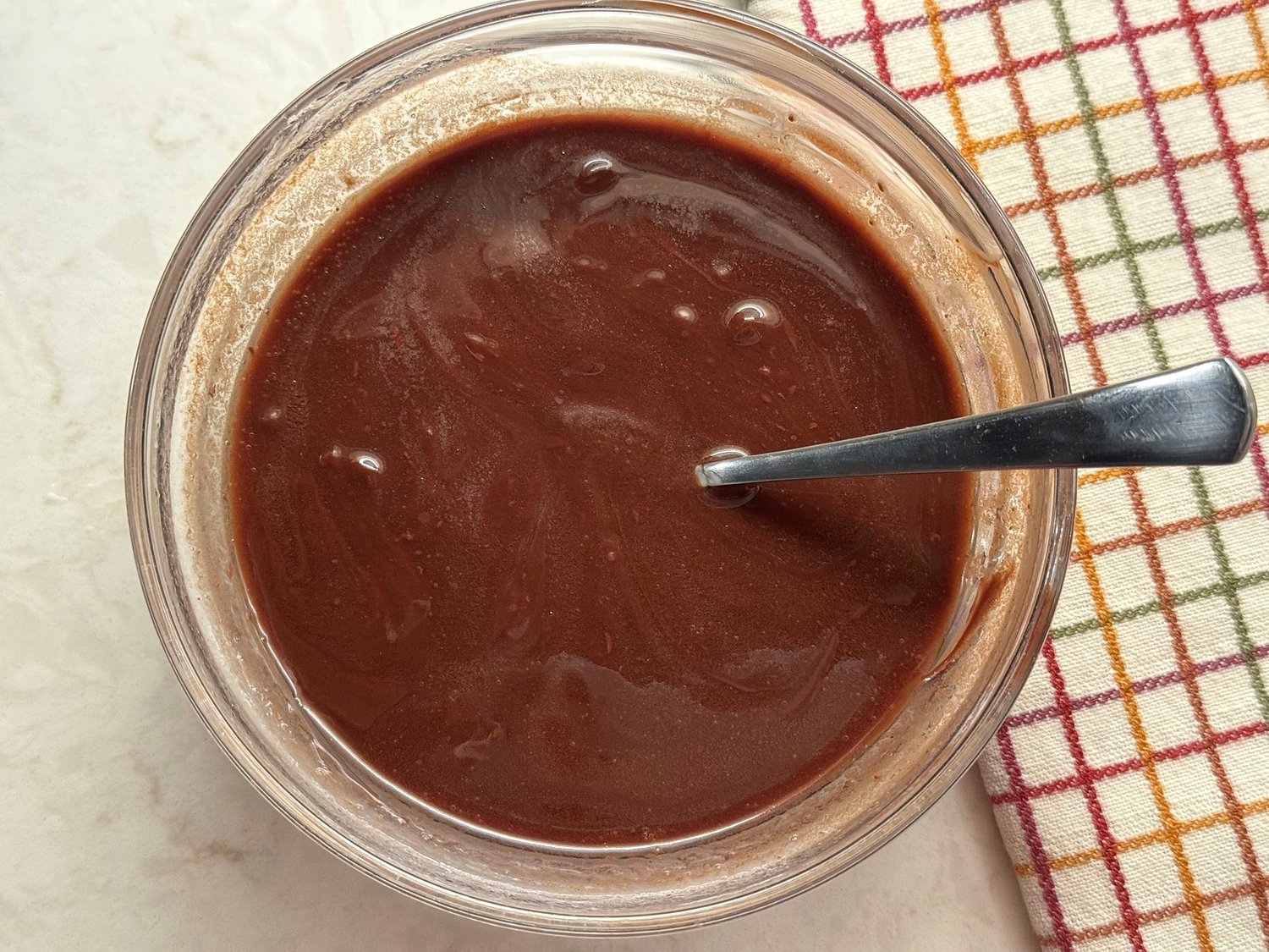 Smooth melted chocolate and butter in a glass bowl with a spoon