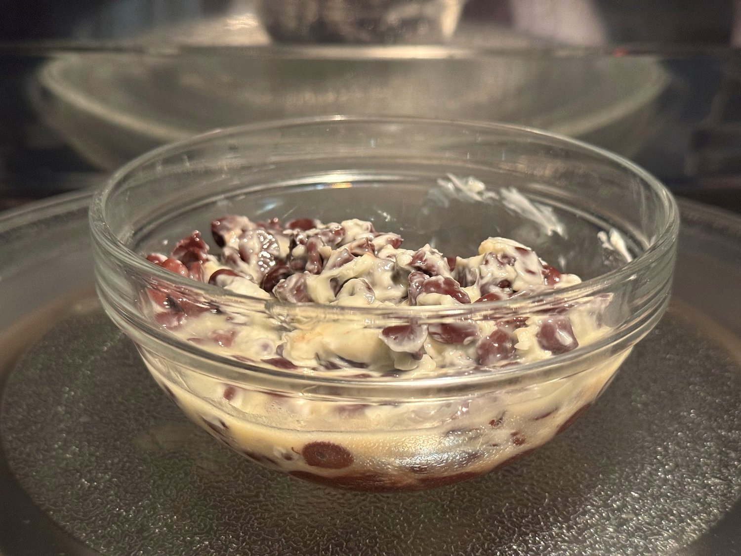 Butter and semisweet chocolate chips starting to melt together in a glass bowl in the microwave