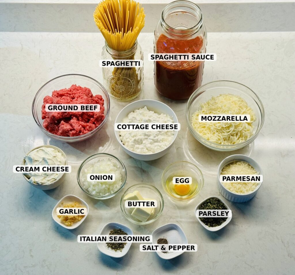 Labeled ingredients for million dollar spaghetti: spaghetti, spaghetti sauce, ground beef, cottage cheese, mozzarella, cream cheese, onion, egg, Parmesan, garlic, butter, parsley, Italian seasoning, and salt and pepper.