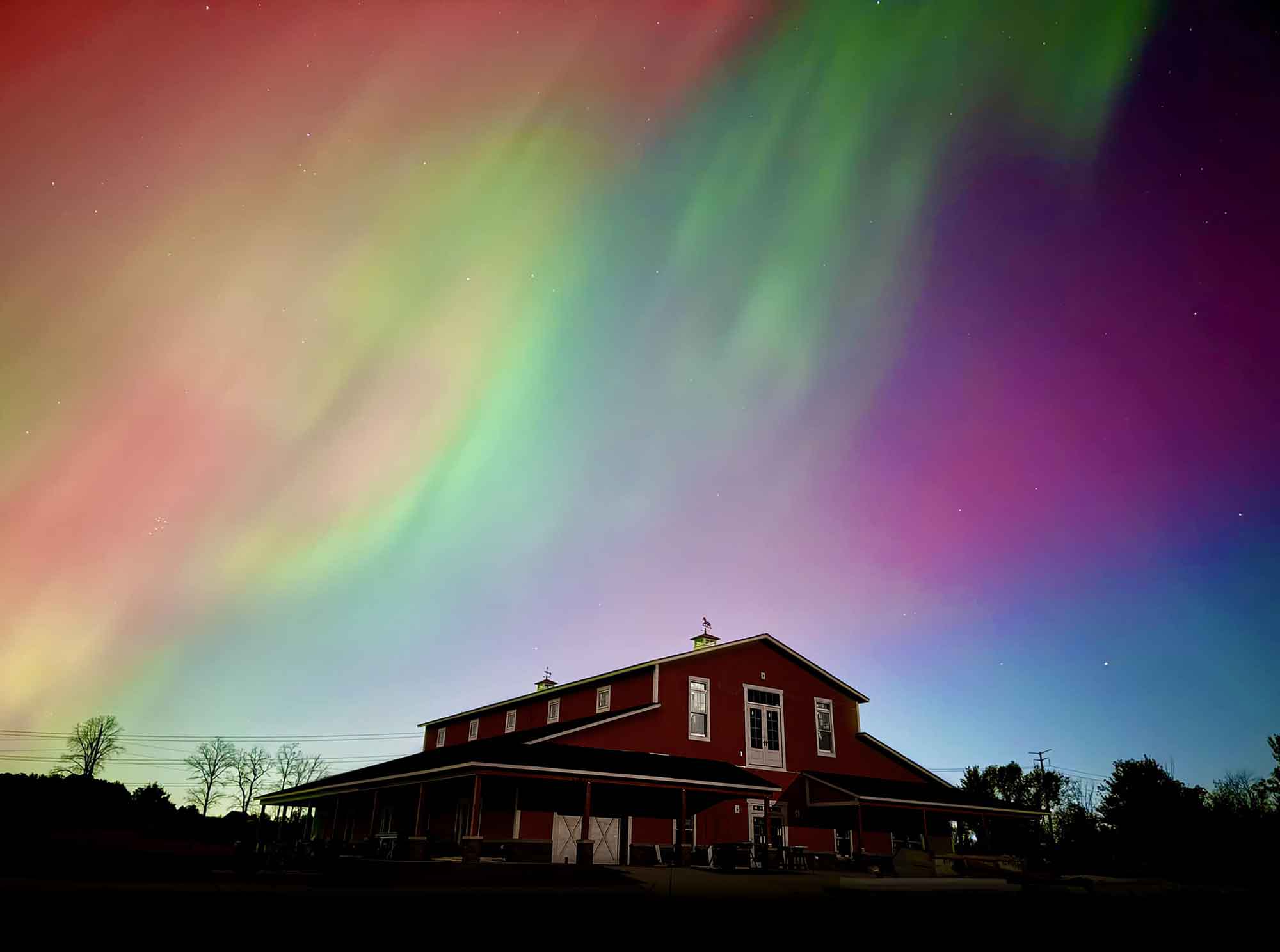 Aurora borealis in pink and green over the red barn at Maker Farm, a first place fair photography entry.