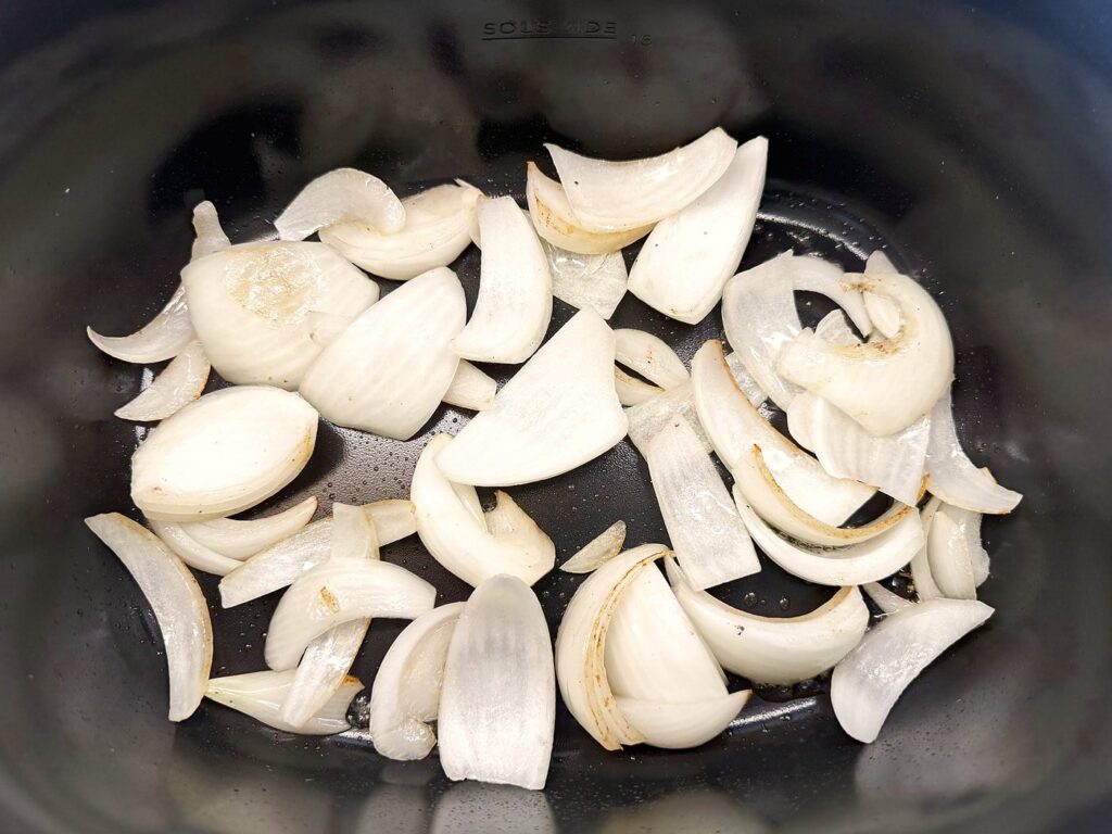 Onion wedges softening in the beef fat left from searing the roast