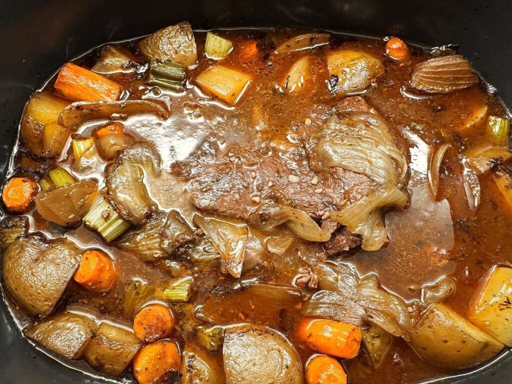 Finished pot roast in the slow cooker after eight hours, fork tender with plenty of gravy