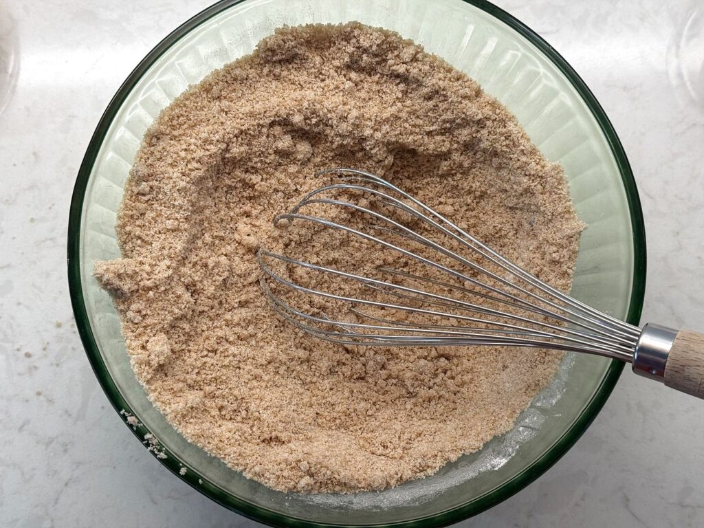 Flour, spices, brown sugar and granulated sugar whisked together into an even tan mixture in a glass bowl