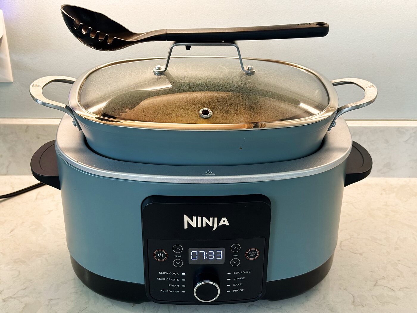 Slow cooker with the lid on, set to low, cooking the pot roast