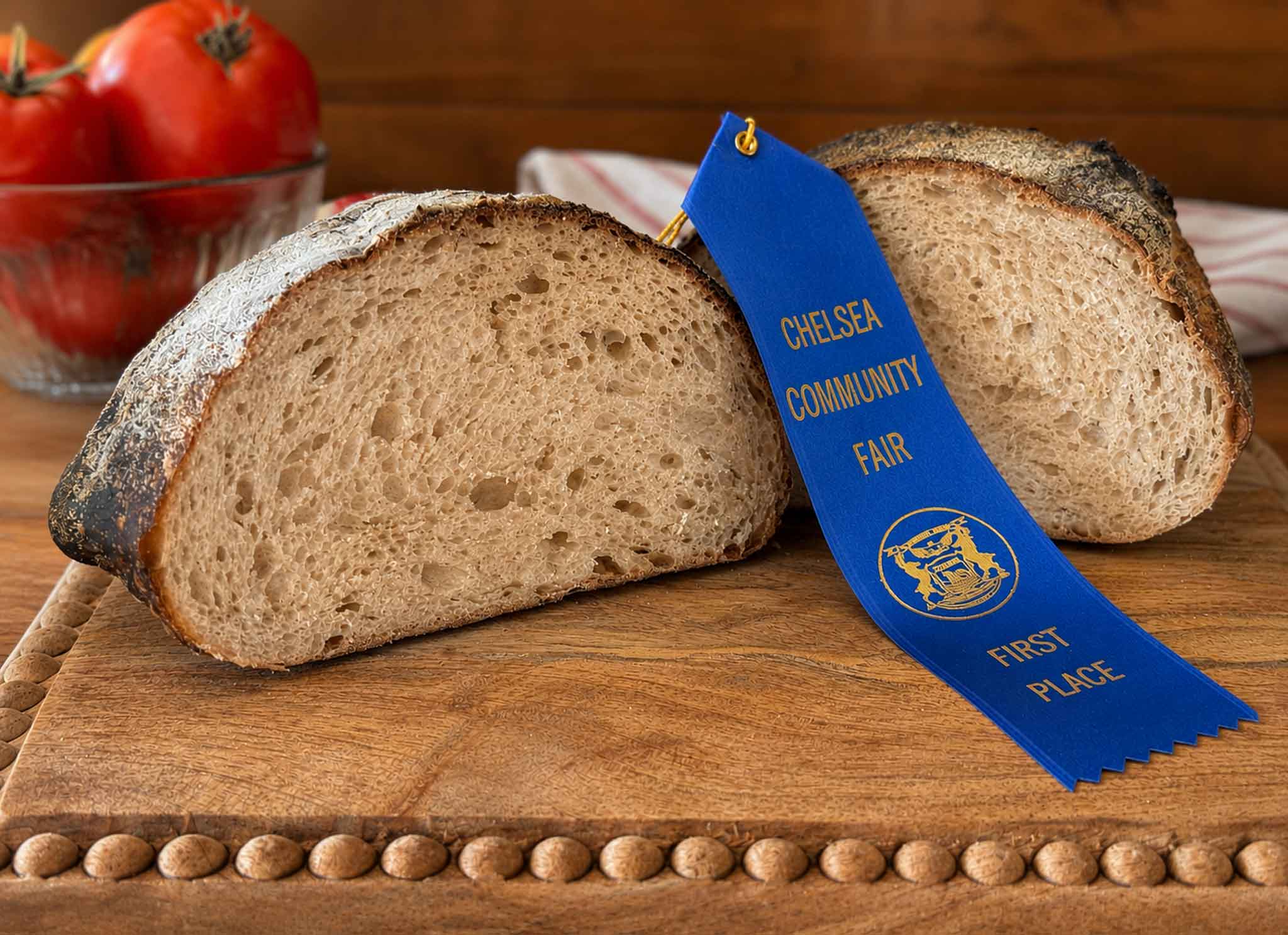 Sourdough bread loaf cut open beside a blue first place ribbon from the Chelsea Community Fair.