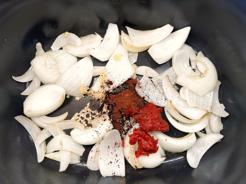 Tomato paste and unsweetened cocoa powder added to the softened onions, the secret ingredient step