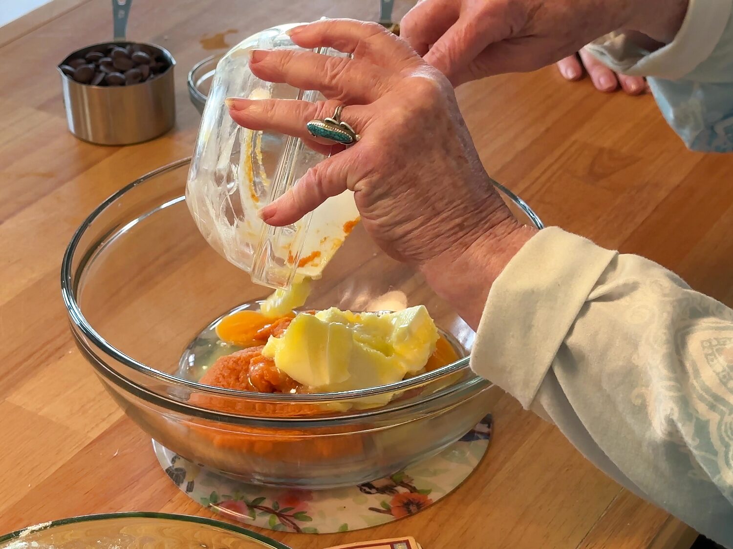 Pouring butter into a bowl of eggs and pumpkin puree