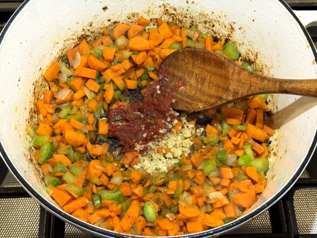 Softened diced carrots, celery, and onion in a white Dutch oven