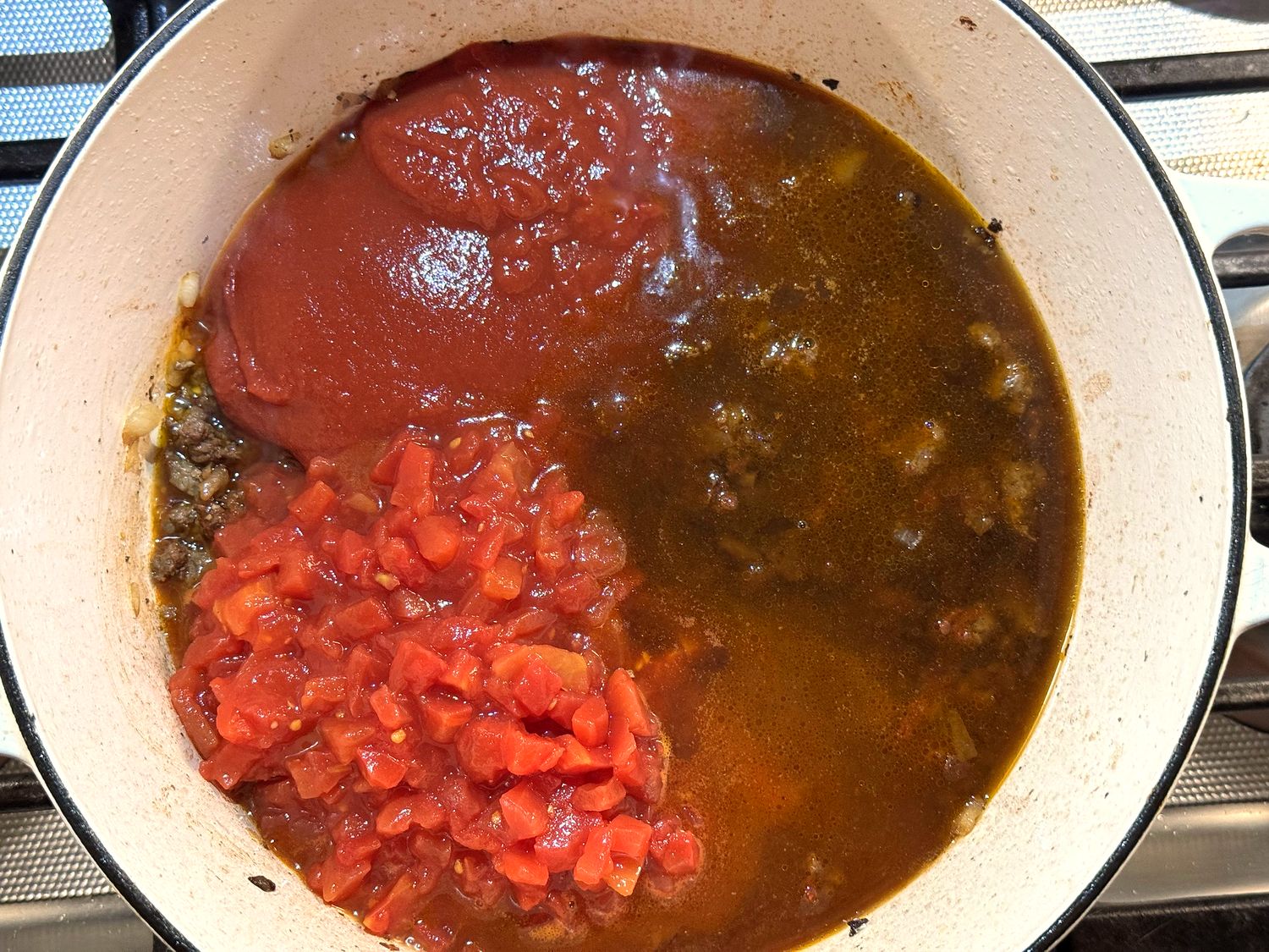 Petite diced tomatoes, tomato sauce, and beef broth added to the browned venison in the Dutch oven
