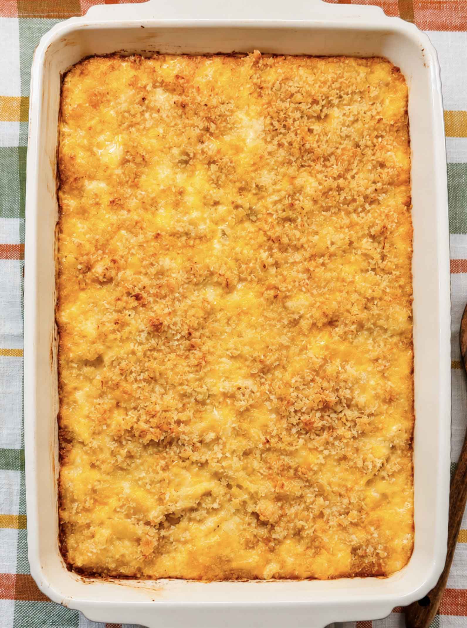 Overhead view of baked mac and cheese with a golden panko crust in a white 9x13 baking dish on a plaid towel