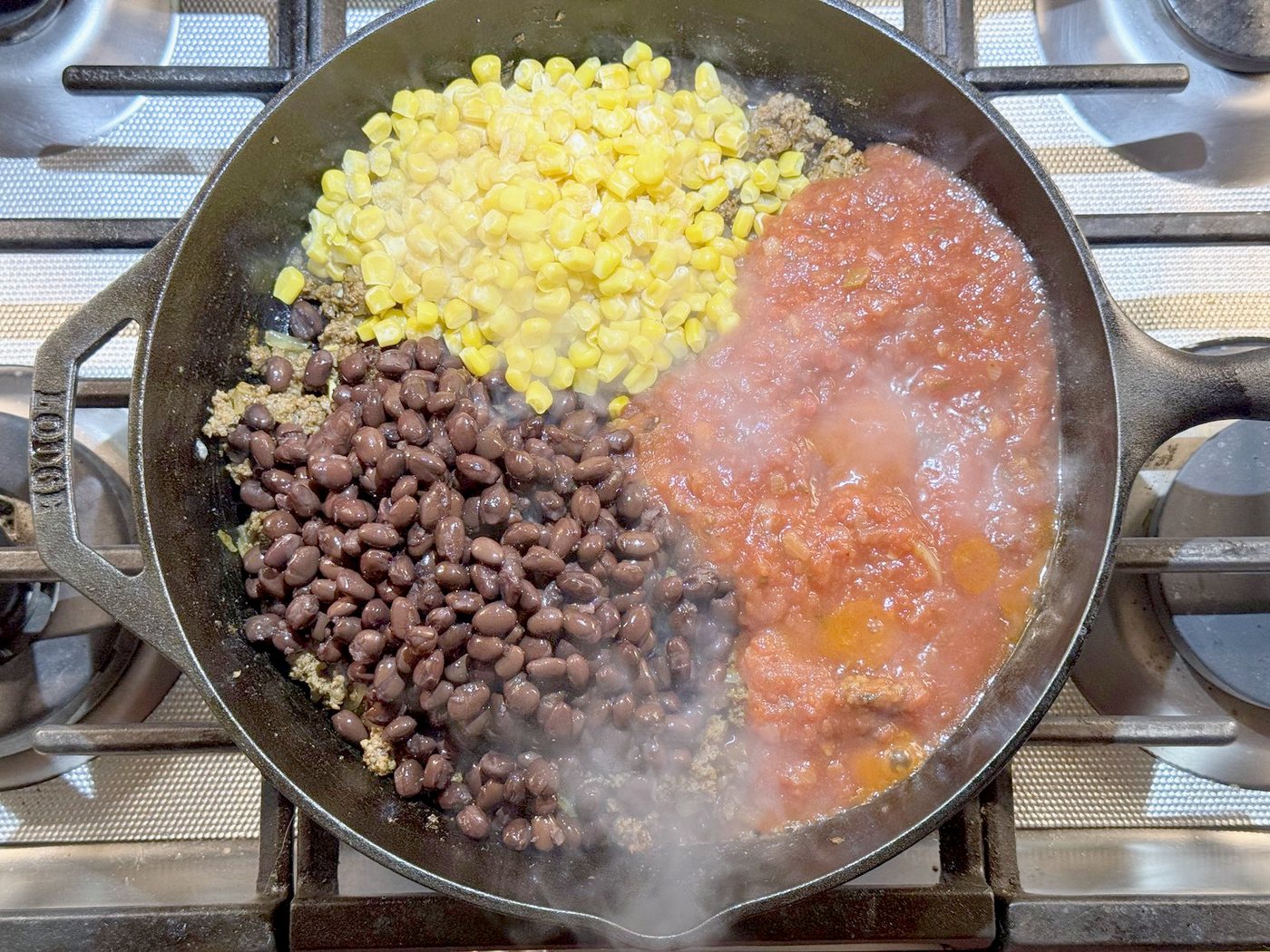 Black beans, corn, and salsa added to seasoned ground beef in a cast iron skillet