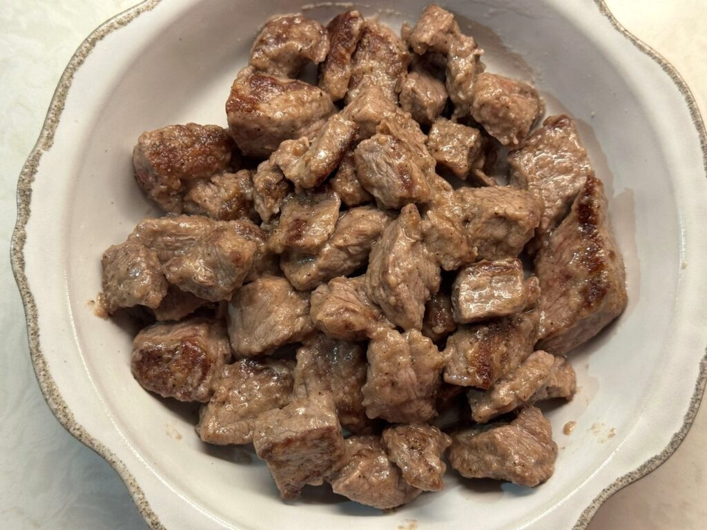 Browned beef stew meat piled on a white plate